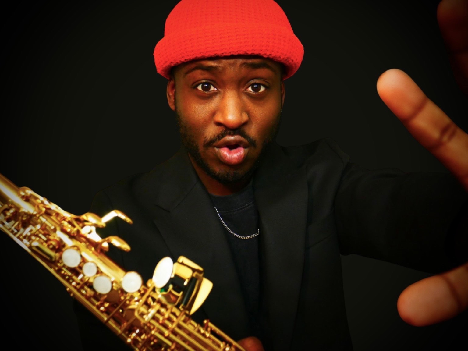 TAVE reaching toward the camera, wearing a red hat