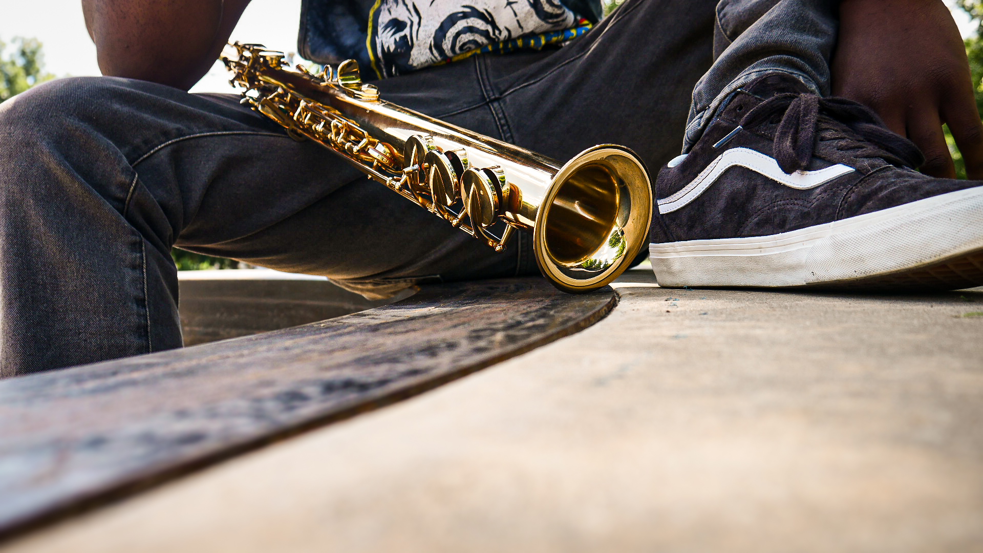 TAVE seated outdoors with his saxophone